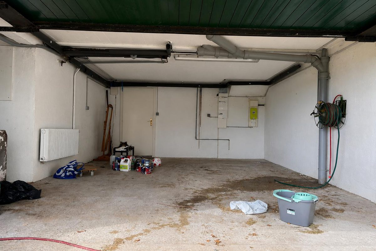 Alte Garage vor dem Rückbau: fleckiger Boden, offene Installationen